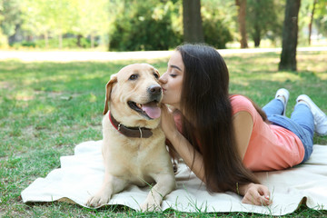 Young woman with yellow retriever resting in park