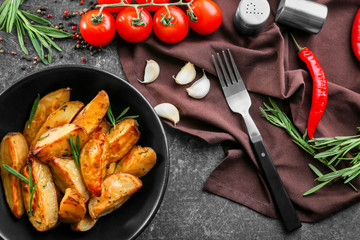 Composition with plate of baked rosemary potatoes on table