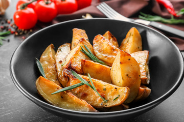 Plate with delicious baked rosemary potatoes on table