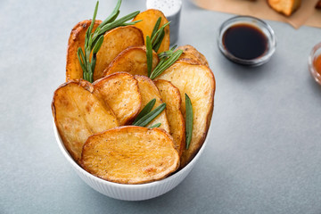 Bowl of tasty rosemary potatoes on table