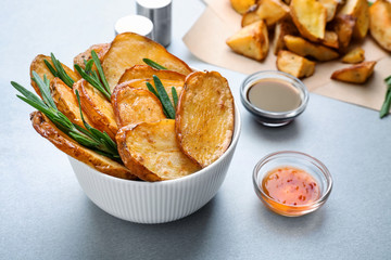 Bowl of tasty rosemary potatoes on table