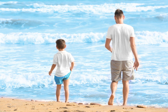 Cute boy with father on sea beach at resort