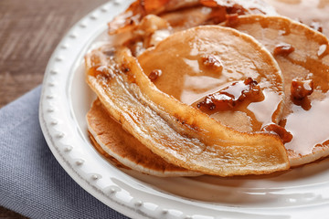 Plate with pancakes, bacon and fried banana on table