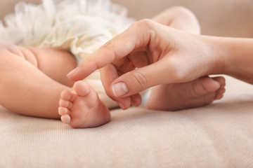 Fototapeta na wymiar Mother touching baby feet on sofa