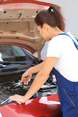 Young female mechanic repairing car outdoors