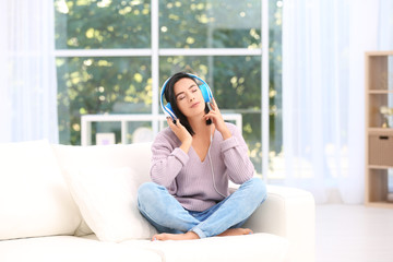 Young woman listening to music through headphones at home