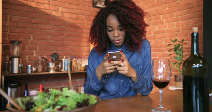 Portrait serious young afro american woman with curly hair use phone in kitchen at home smiling message pc phone type casual internet adult cell phone chat communicate Slow Motion Shot