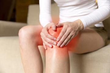 A young woman massaging her painful knee