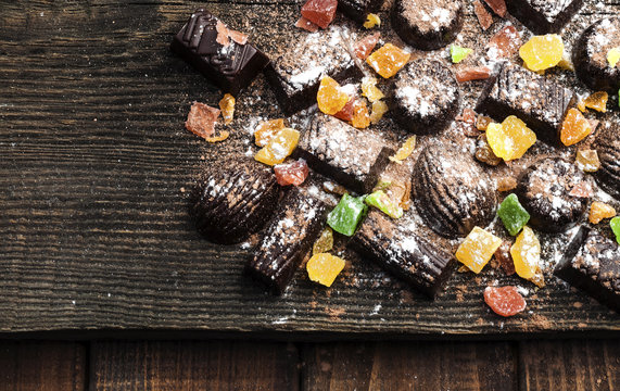 chocolate candies, candied fruits on a wooden background