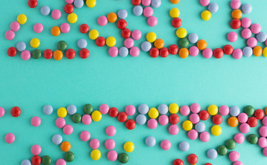 colorful chocolate candy group on blue mint background free space top view
