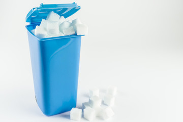 Blue trash can full of sugar cubes, white background