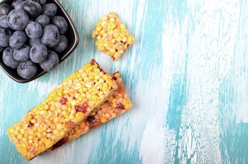 Muesli bars with berries on wooden background
