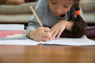 Little asian girl writing paper and lying on floor