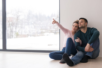 young couple sitting on the floor near window at home