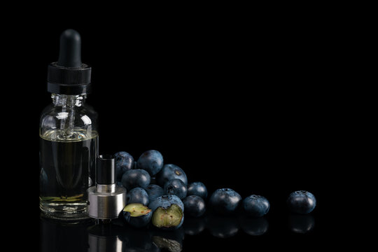 tank of electronic cigarette on a black background and a bottle of blueberry taste. Advertising concept for wapes on a black background