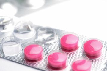 used blister pack of magenta tablets, medical pills in silver foil pack on white background.