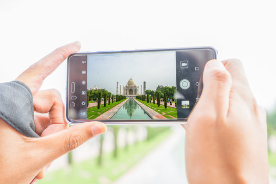 tourist taking photos of Haj Mahal with mobile phone