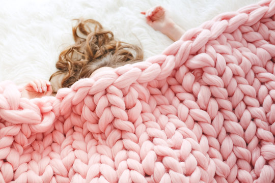 Young woman sleeping under warm peach color throw blanket