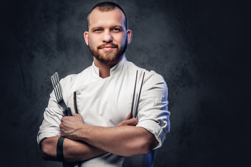 Chef cook holds a knife over dark grey background. - obrazy, fototapety, plakaty