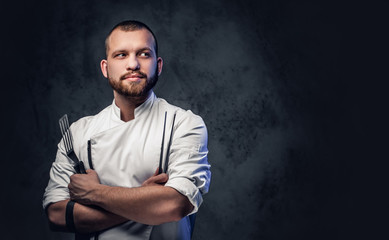 Chef cook holds a knife over dark grey background.