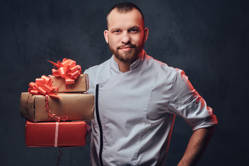 Chef cook holds colorful paper Christmas gifts.