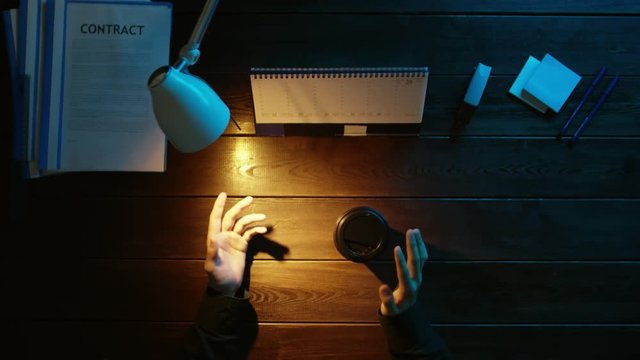 A man is sitting at an office desk and using a phone.