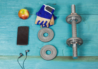 Sport items bottle, dumbbells, gloves on the sport flooring