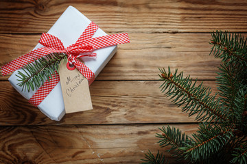 Holiday gift box. Christmas present with tag at white wooden background.