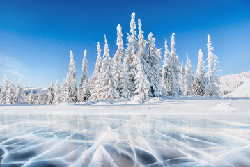 Blue ice and cracks on the surface of the ice. Frozen lake under a blue sky in the winter. The...