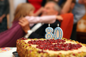 Eighty birthday Grandfather with granddaughter and family with number 80 on cake