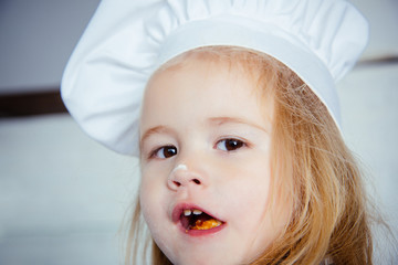 Baby boy with flour on nose in white chef hat