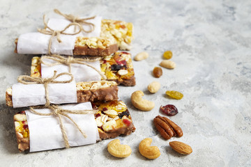 Fototapeta na wymiar Healthy granola bars with nuts, seeds and dried fruits on the gray texture table, with copy space.