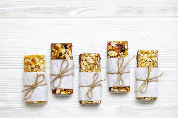 Various granola bars on white wooden background
