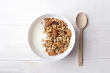 Bowl of whole grain muesli with yogurt on white wooden background, top view