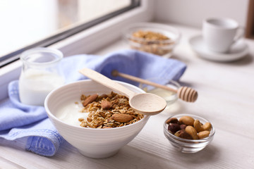 Healthy breakfast. Yogurt with granola and nuts on window sill