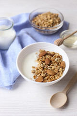 Homemade healthy granola or muesli with yogurt on white wooden background