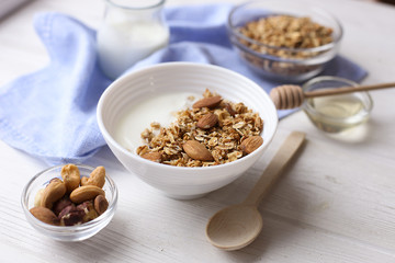 Homemade healthy granola or muesli with yogurt on white wooden background