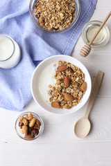 Homemade healthy granola or muesli with yogurt on white wooden background