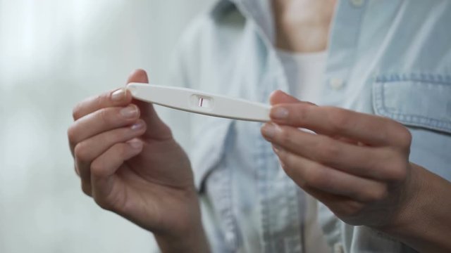 Woman enjoying negative pregnancy test result, showing it into camera, close-up