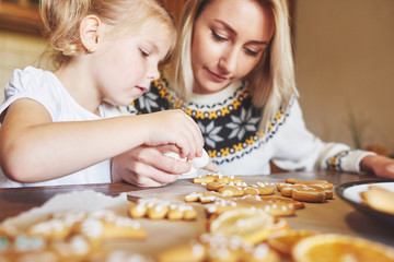 Confectionery workplace with women's hands decorating Christmas cookies. Home bakery, sunny sweet, winter holidays.