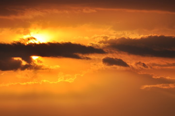 sun hides behind clouds at sunset
