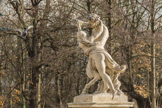 Sculpture of Satire and Nymph catching grapes from his hand, 1777, the autumnal trees and flying pigeon in the background, the Royal Baths Park in sunlight, Warsaw, Poland