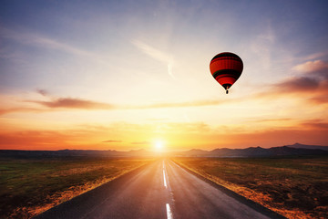 Asphalt road along and Colored ball in the sky at sunset