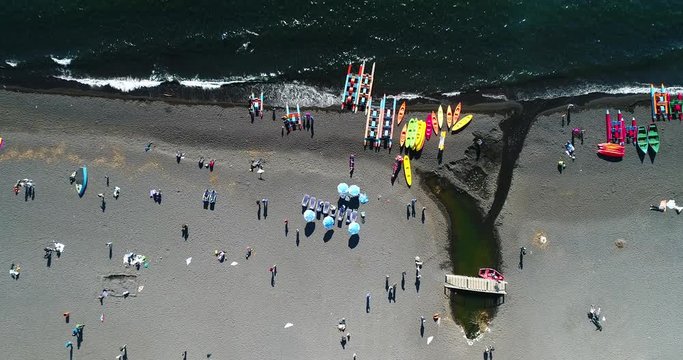 Aerial Birds Eye View Black Sand Beach People Kite Flying Windy Day Waves Crashing- Pucon Chile