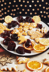 Christmas gingerbread cookies and dried orange and spices on white table. Pastel, jam in rolls on a plate