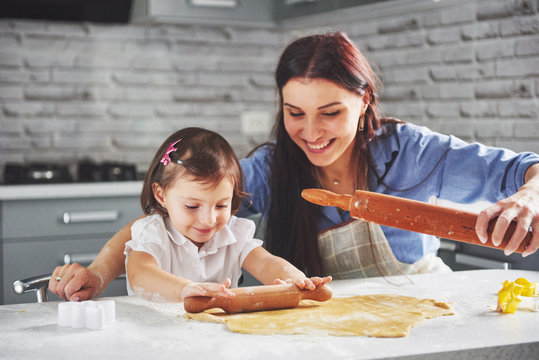 Happy family in the kitchen. Holiday food concept. Mother and daughter preparing the dough, bake cookies. Happy family in making cookies at home. Homemade food and little helper