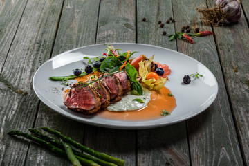 Tasty medium rare meat steak with sauce and salad. Gourmet meal made of meat fillet and vegetables. Delicious healthy food.