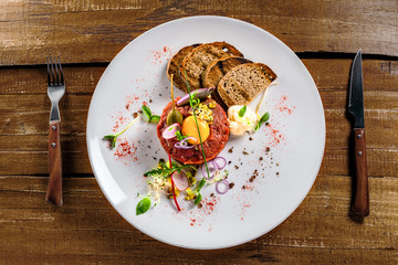 Tasty tartare with toasted bread and salad. Gourmet French meal made of raw ground meat. Delicious healthy food. Top view.