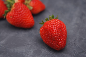 Fresh Strawberry Close Up on Gray Background with blurred strawberries on background. Summer Strawberry.