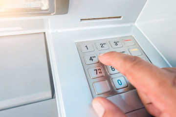 closeup ATM machine and finger hand entering pressing password for withdrawing money banknotes.